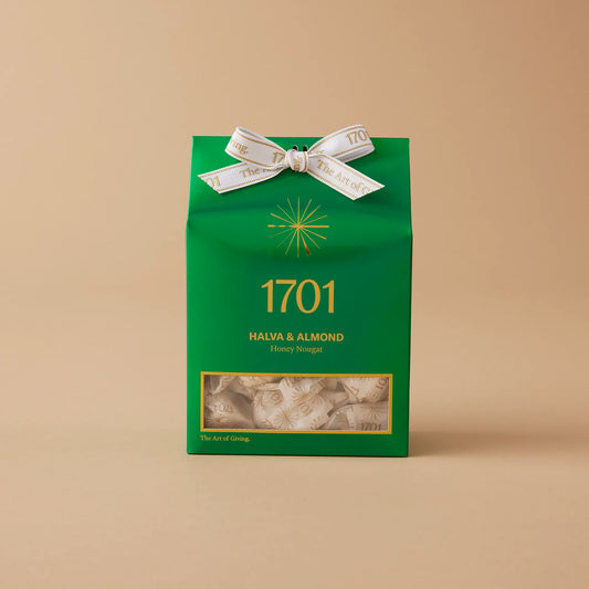 160g box of Halva & Almond Honey honey nougat, presented in a light green box. The box is shown on a warm background, with the product label visible on the front of the box. The nougat pieces are visible inside the box, and the box is tied with a ribbon.