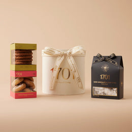The Essential Gift Box is presented on a warm background. The gift box includes a box of handcrafted honey nougat and two boxes of biscuits, featuring some of the favorite flavors of the makers. This gift box is a perfect way to indulge in some of the most delicious treats, either for yourself or for someone special. 