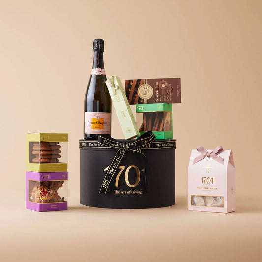  A luxurious gift box presented in a signature hat box featuring a bottle of Veuve Cliquot Rosé, a box of handcrafted honey nougat, a nougat bar, and a selection of chocolates and confections. The perfect gift for celebrations and special occasions, sure to make it extra special.