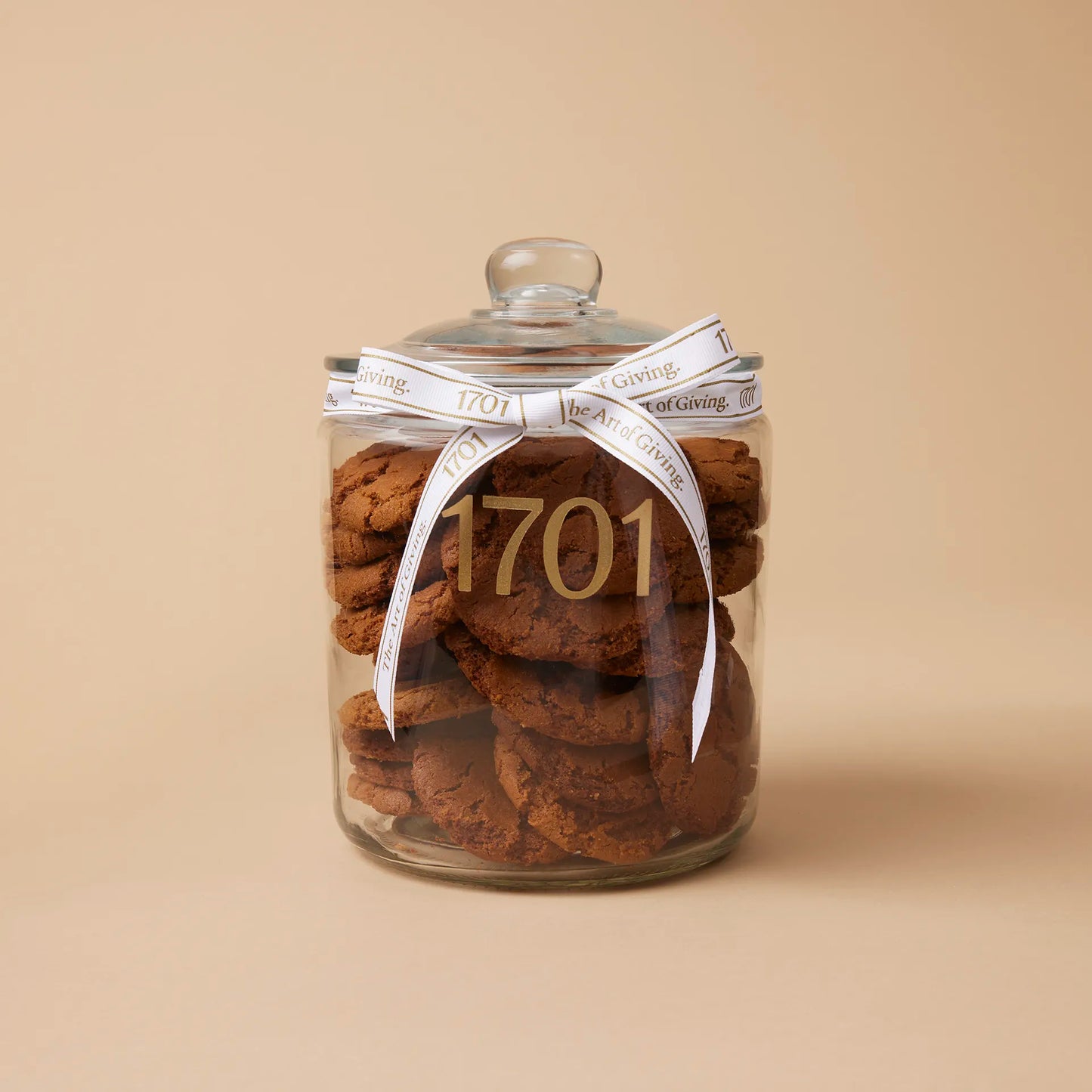 A 1kg glass jar of handmade ginger biscuits, presented in a glass jar with a hand-tied signature ribbon on a warm background, with the product label visible on the front of the jar. The biscuits are SANHA Halaal approved, making them a perfect gift idea for anyone who appreciates high-quality biscuits made with care.