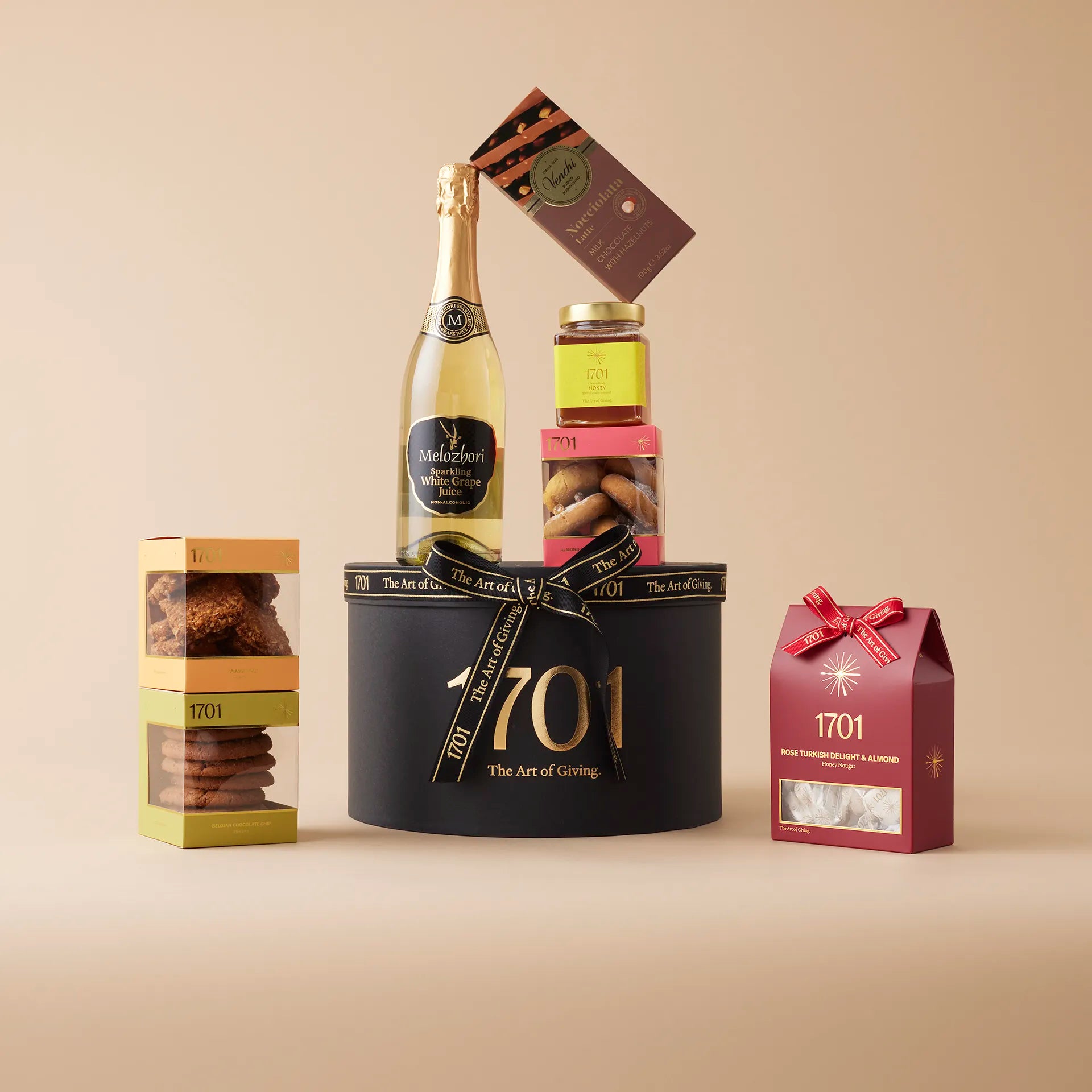 The Luxury White Grape Juice Gift Box is presented on a warm background. The gift box includes handcrafted honey nougat, incredible biscuits, 1701 farm honey, imported Italian chocolate, and Melozhori white grape juice. This gift box is perfect for those who appreciate celebrations without alcoholic drinks and the luxury of fine treats. The brown and gold design adds a touch of elegance, making it perfect for any occasion.