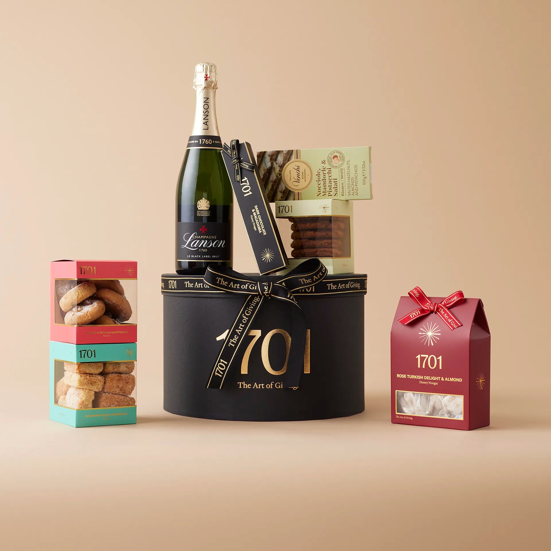 A gift box featuring a bottle of Lanson Black NV Brut and a selection of sweets. The box includes a box of handcrafted honey nougat, a nougat bar, a hand-picked selection of biscuits, and an imported Italian chocolate. The product is presented on a signature hat box.