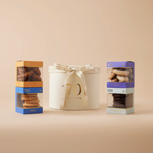 A medium-sized gift box filled with four different flavors of biscuits. The biscuits are handmade and come in a variety of shapes and sizes. The box is decorated with a hand-tied ribbon and label that identifies the contents. It's perfect for anyone who loves delicious and unique biscuits.